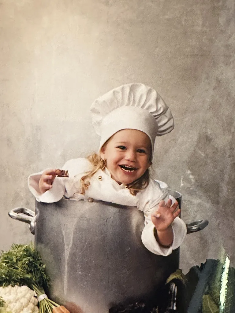 Florry als baby in een grote kookpot, met een koksmuts op